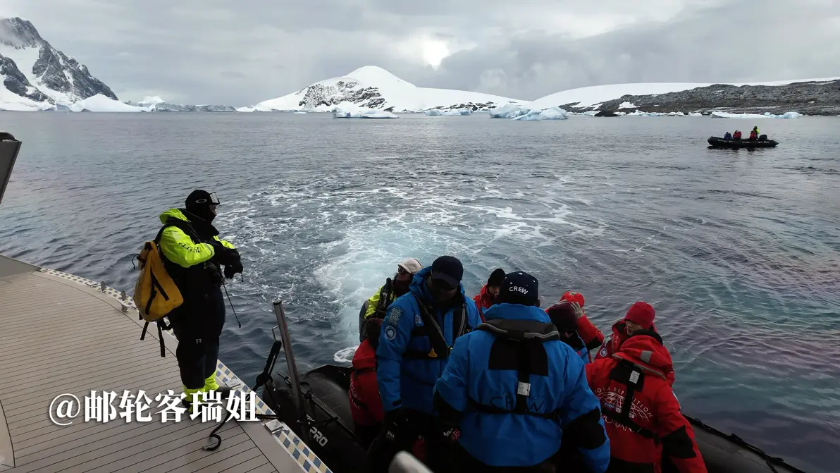 旅客在岸边准备登上冲锋艇,远处是雪山与海湾