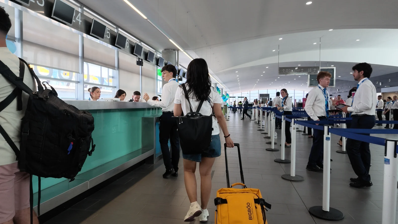 邮轮航站楼内,旅客提着行李排队办理登船手续